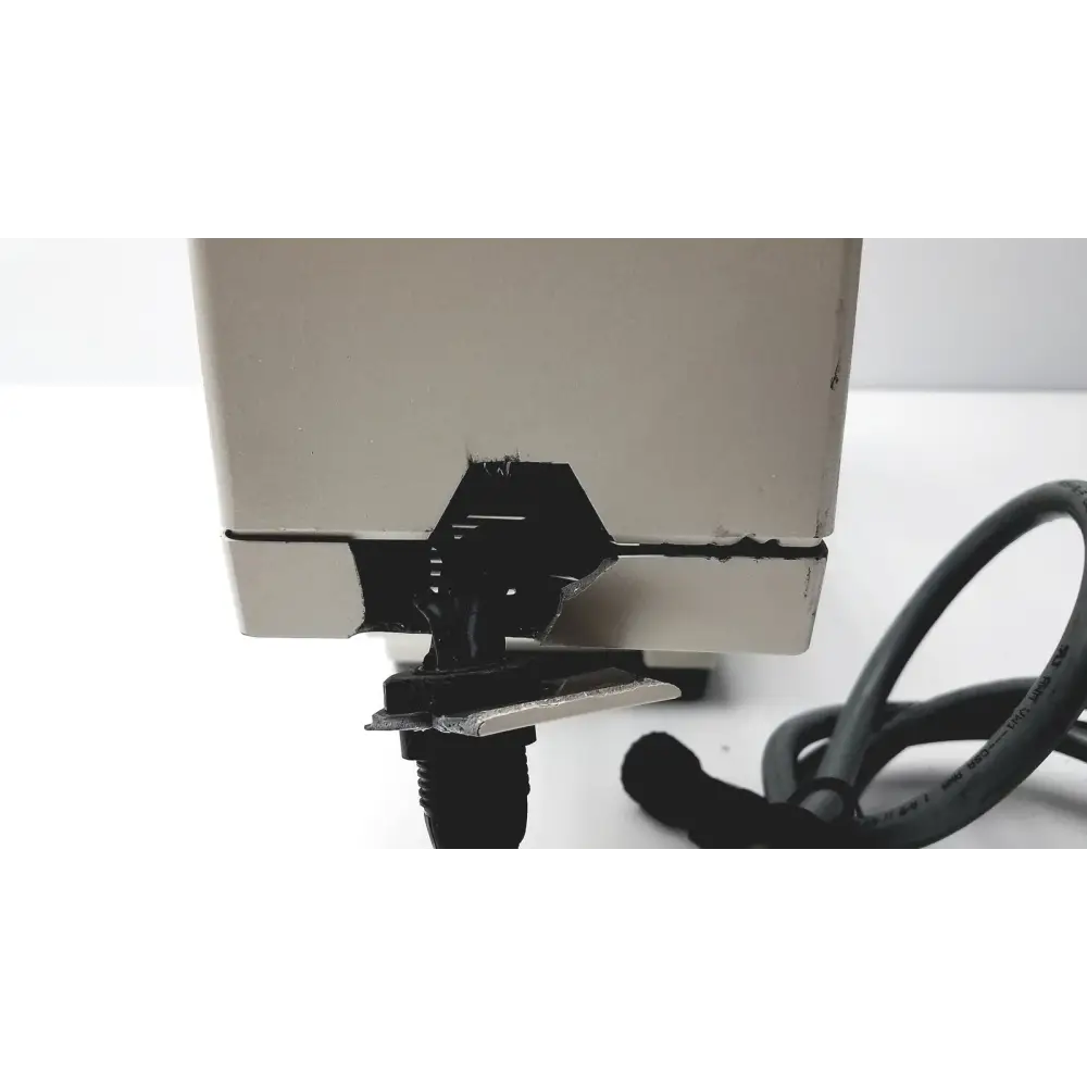 Beige rectangular electronic device with a black damaged section and attached cable.