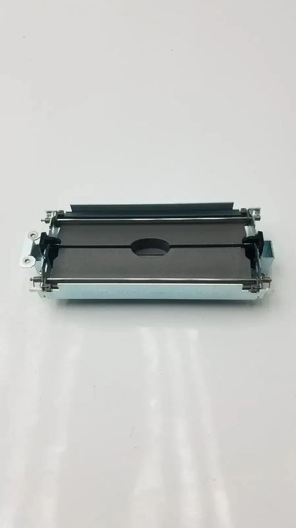 Silver-toned metal printer ribbon cartridge with black plastic parts and central oval cutout for assy secondary barrier