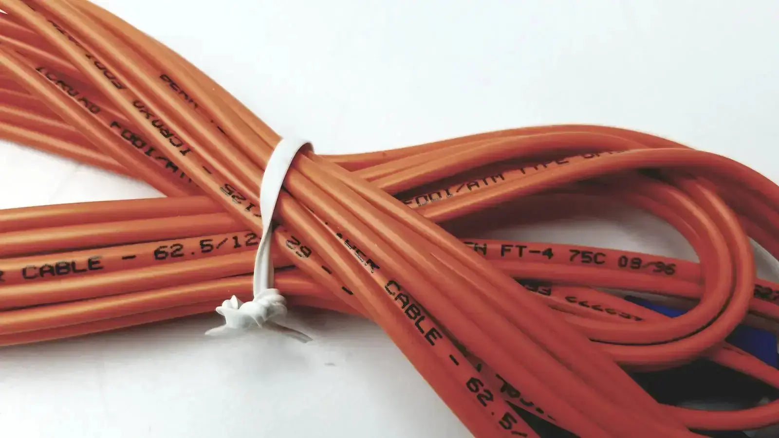 Orange insulated optical fiber cable berk-tek icr0x0 neatly bundled with white tie suitable for hospital surplus use