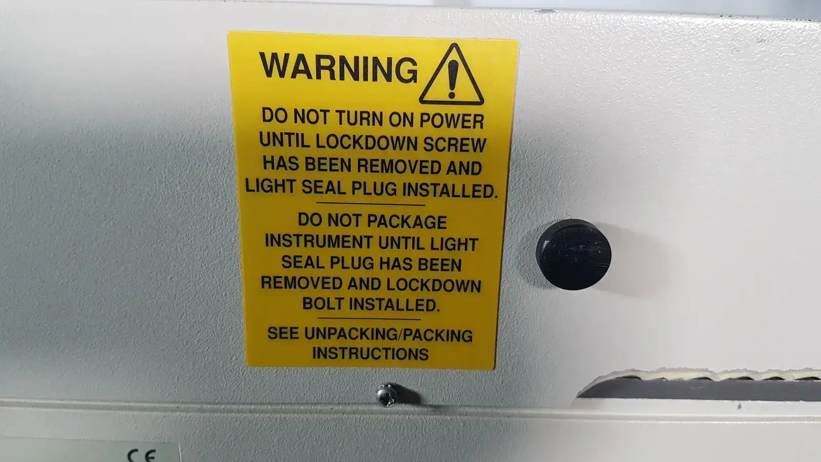 Yellow warning label with black text and caution symbol on white surface of bio rad molecular imager fx machine