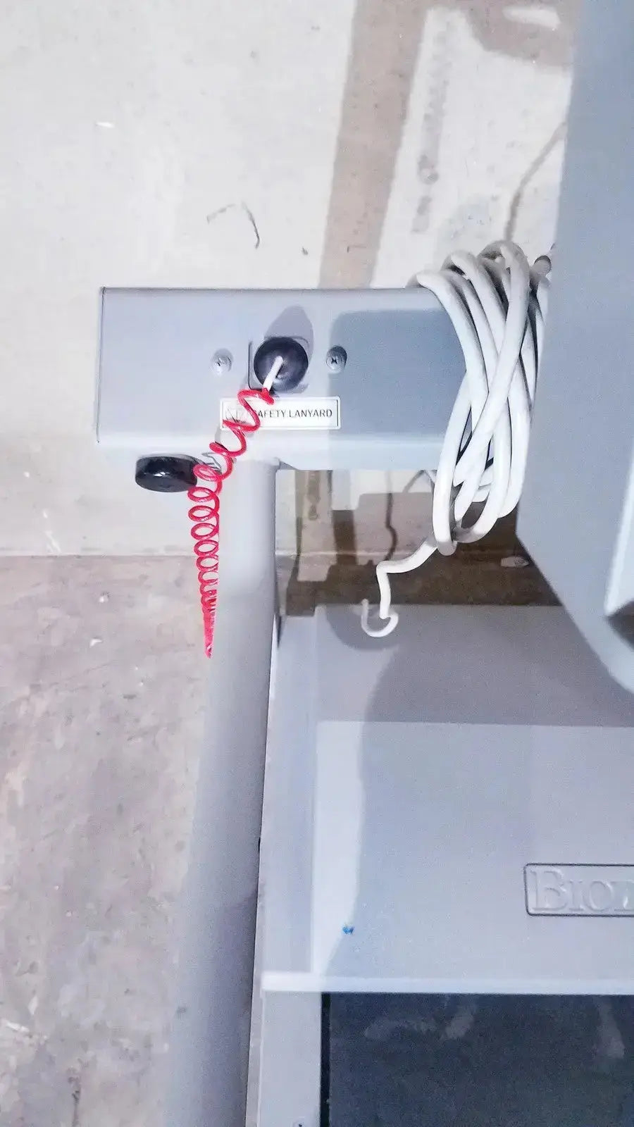 Gray metal industrial control panel with coiled red and white cable on the back of biodex gait trainer ii treadmill