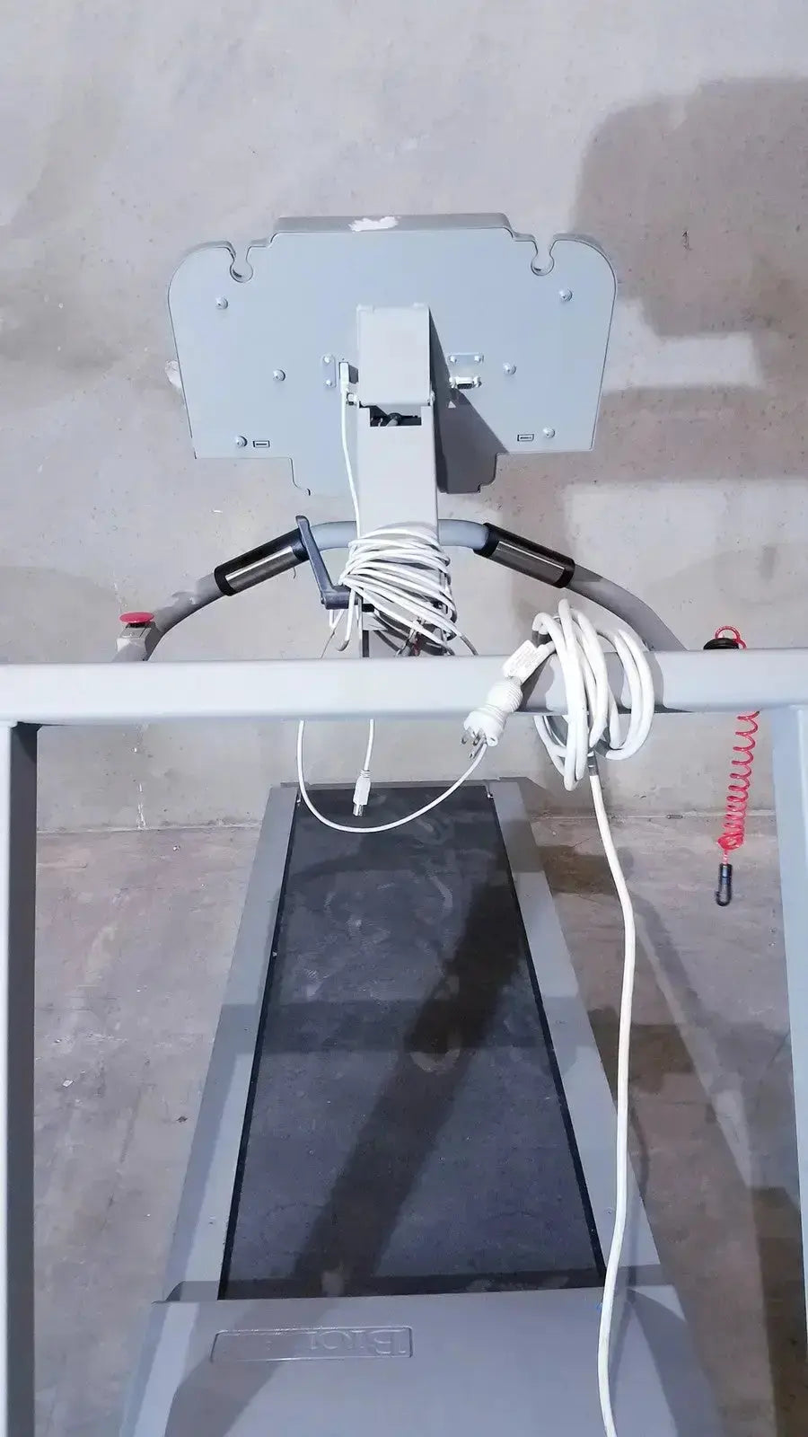 Gray biodex gait trainer ii treadmill with digital display and coiled white cables hanging from its frame