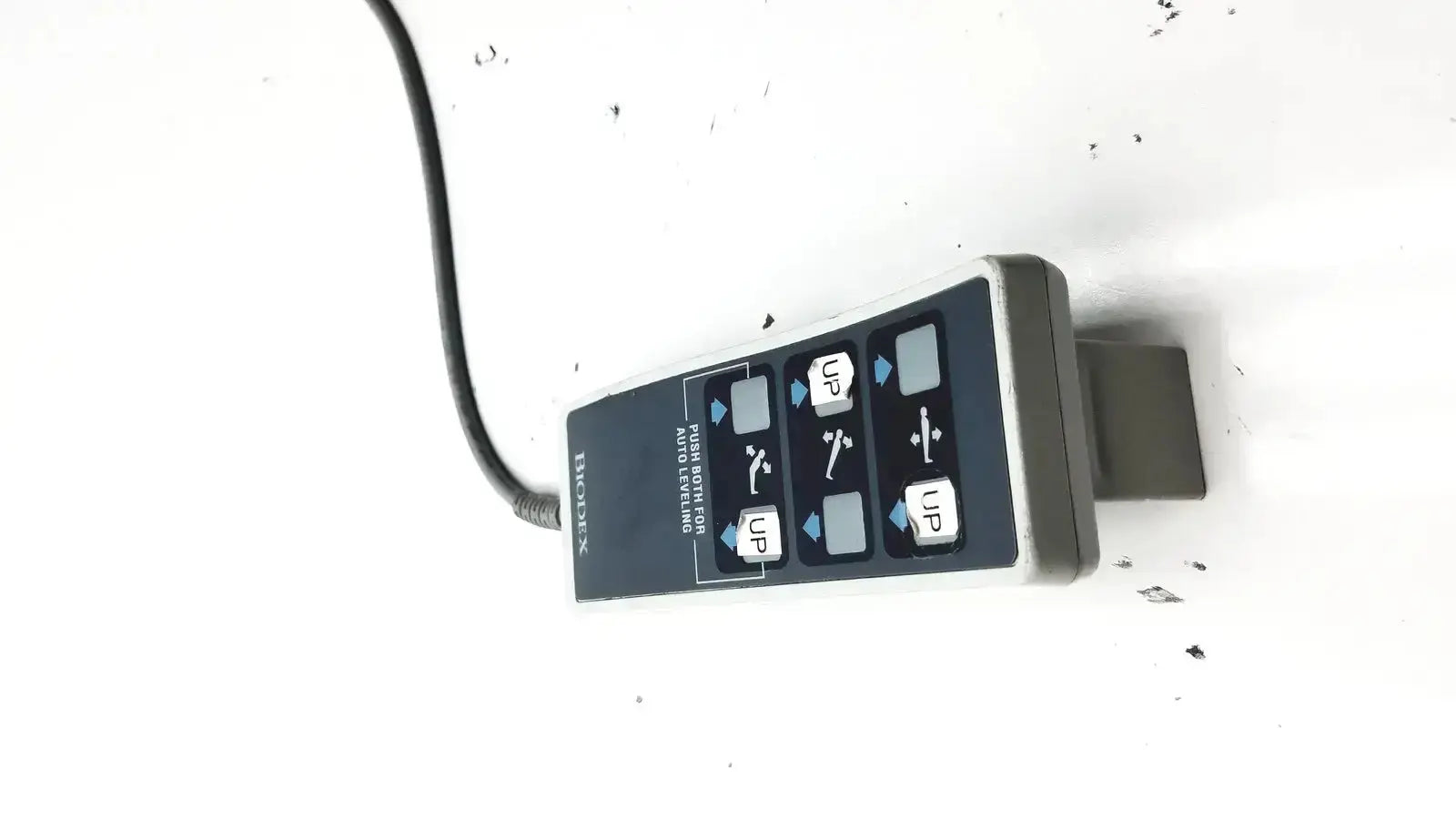 Black and gray handheld remote controller with labeled directional buttons for Biodex ultrasound table use