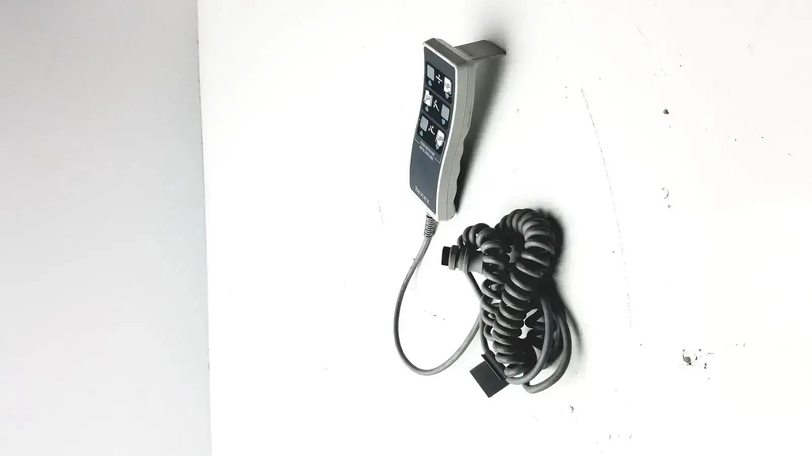 Gray handheld remote controller with coiled black cable for biodex ultrasound table remote use