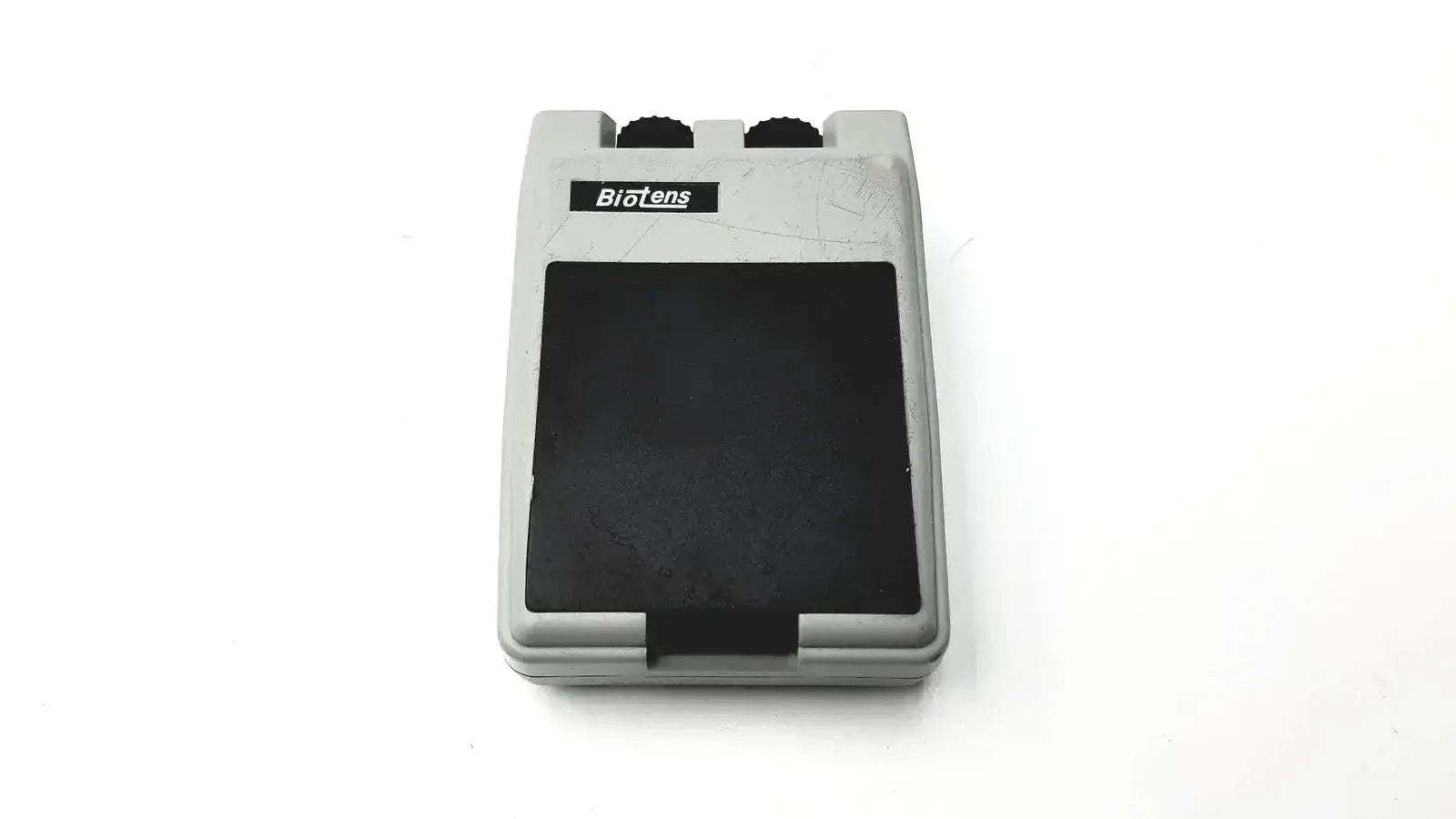 Gray plastic biotens transcutaneous electrical nerve stimulator foot pedal with black rubber top and two black knobs on upper edge