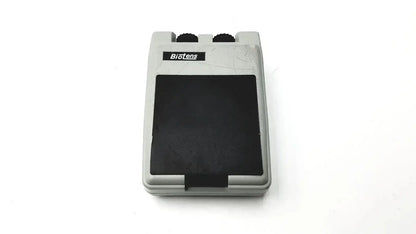 Gray plastic biotens transcutaneous electrical nerve stimulator foot pedal with black rubber top and two black knobs on upper edge