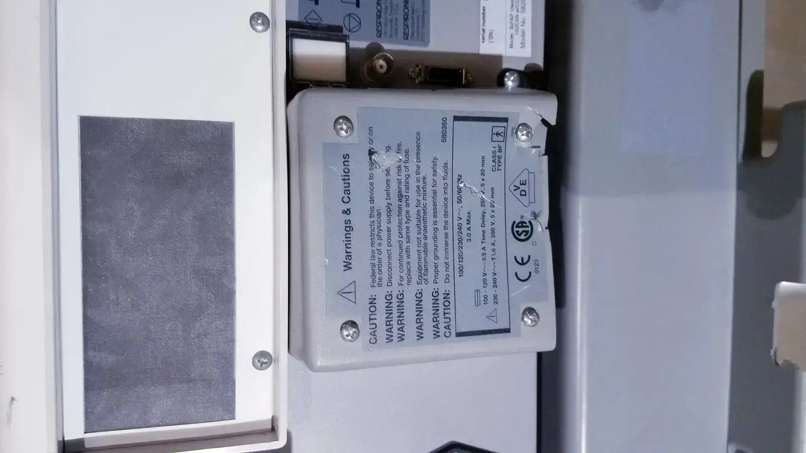 White rectangular electronic component with printed warnings on the back of bipap vision ventilatory support system 582059 with stand