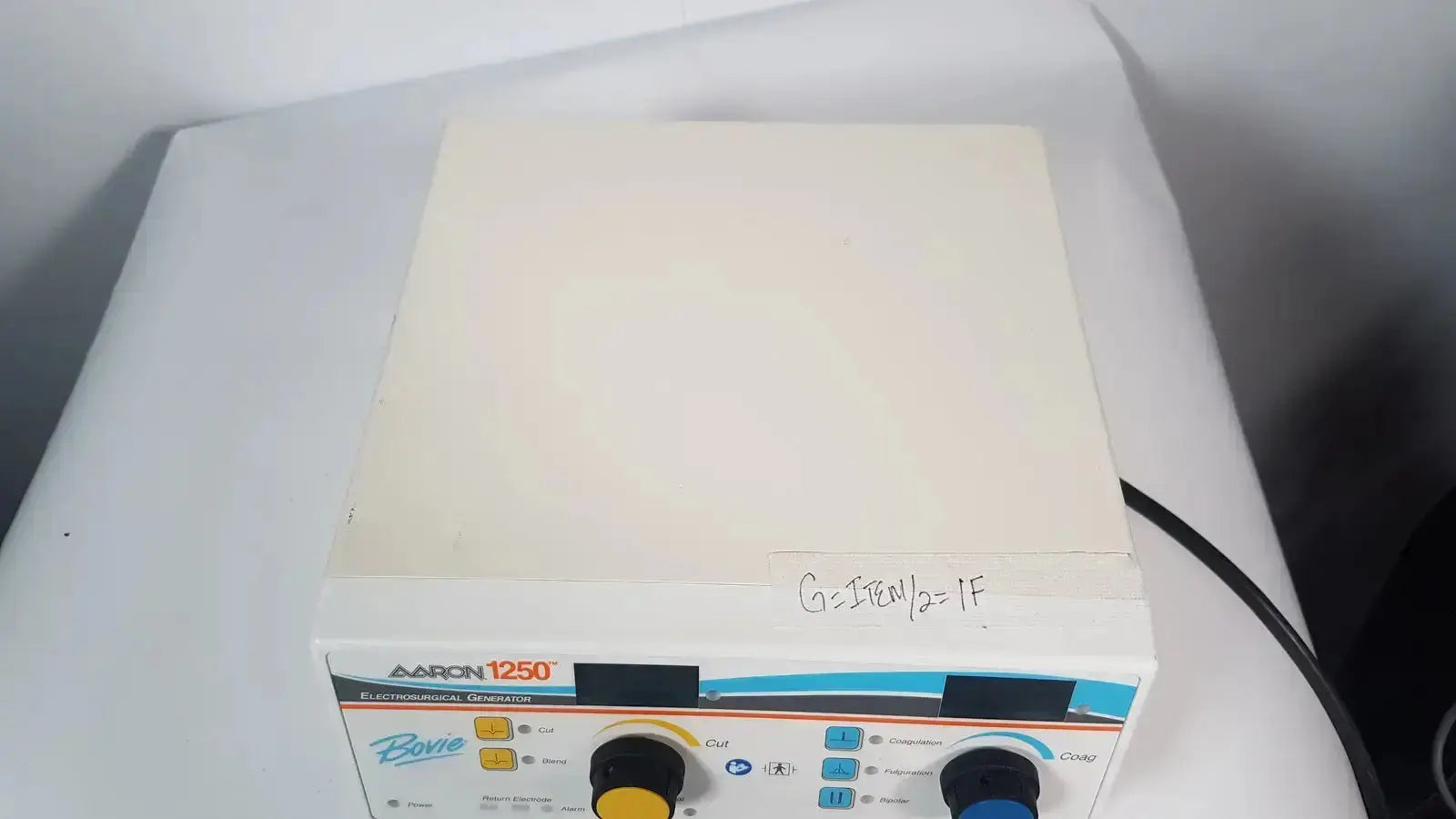 White rectangular bovie aaron 1250 electrosurgical generator with blue and black control panel and yellow knobs from hospital surplus