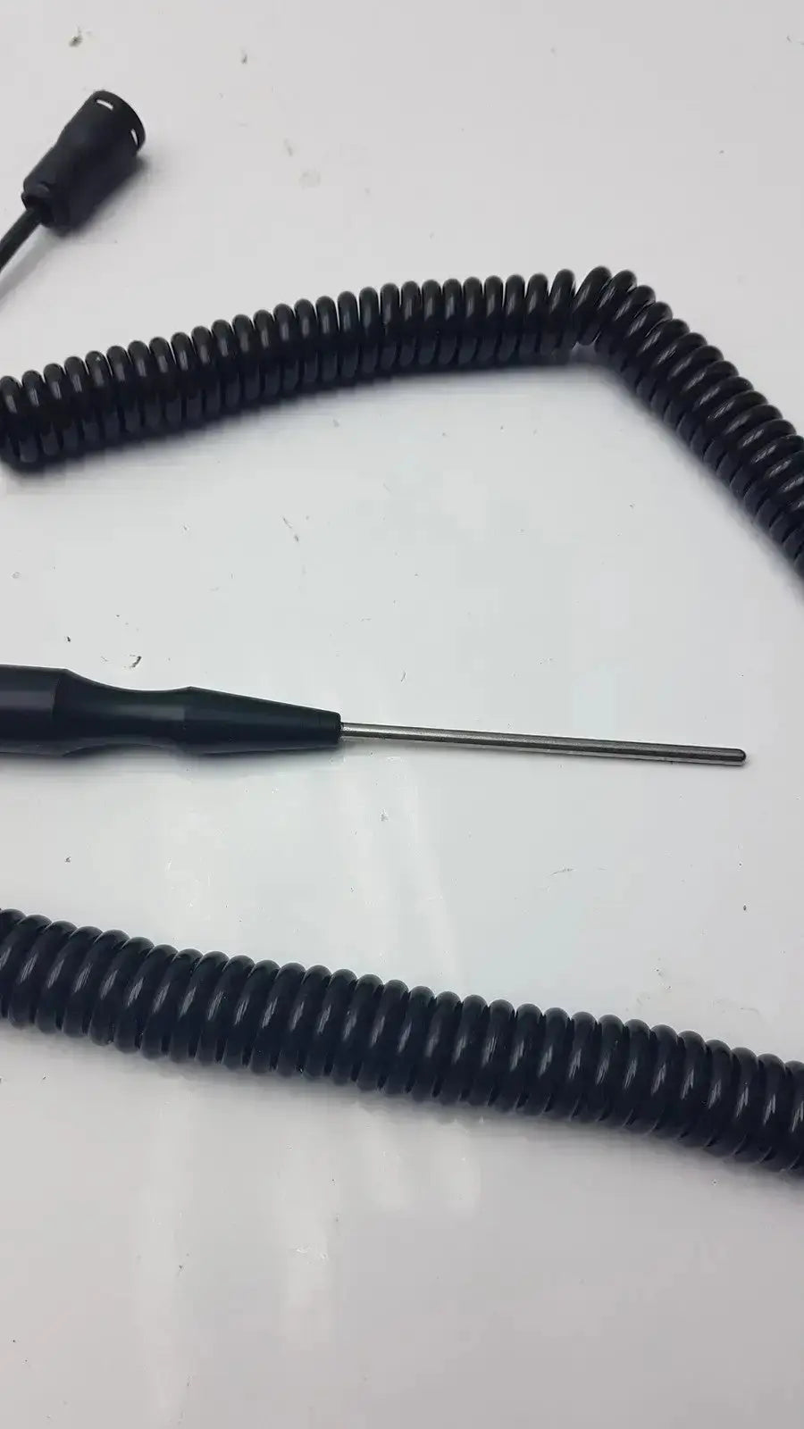 Black coiled thermometer probe with metallic tip and connector end for biomedical technicians from hospital surplus