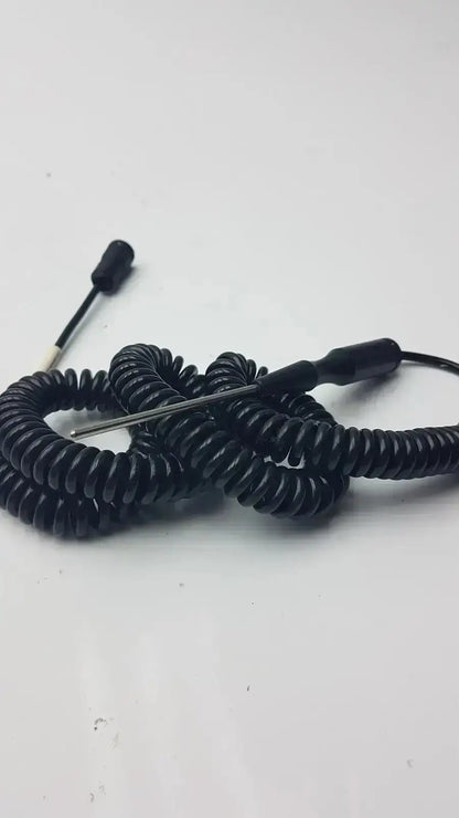 Black coiled thermometer probe with metallic tip and black connectors used by biomedical technicians from hospital surplus