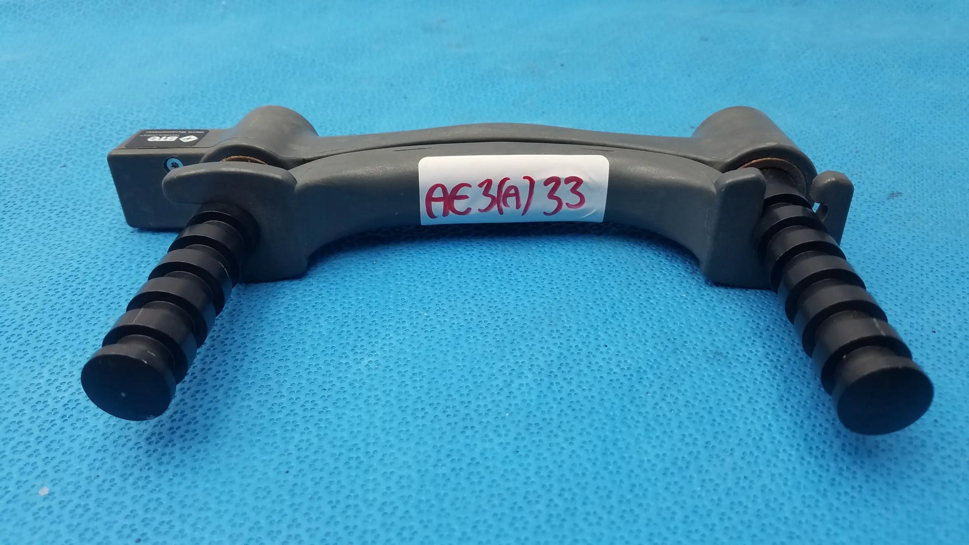Black plastic dental handpiece holder with textured grip and labeled tag for BTE Technology hydraulic hand dynamometer