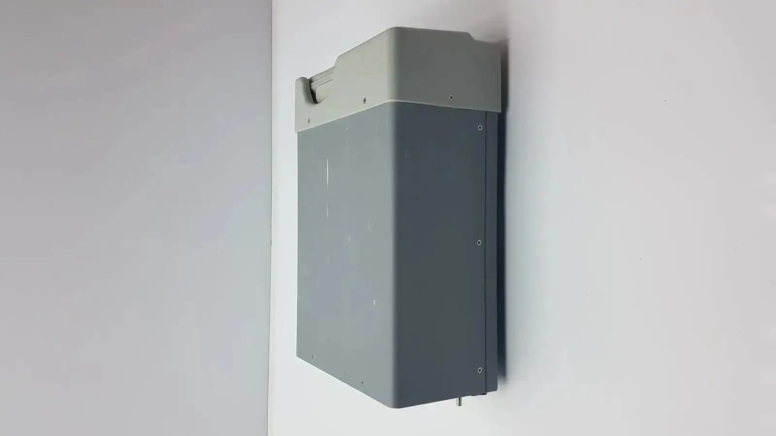 Gray rectangular wall-mounted battery unit with lighter top section and mounting hardware for buffalo filter virovac smoke evacuation