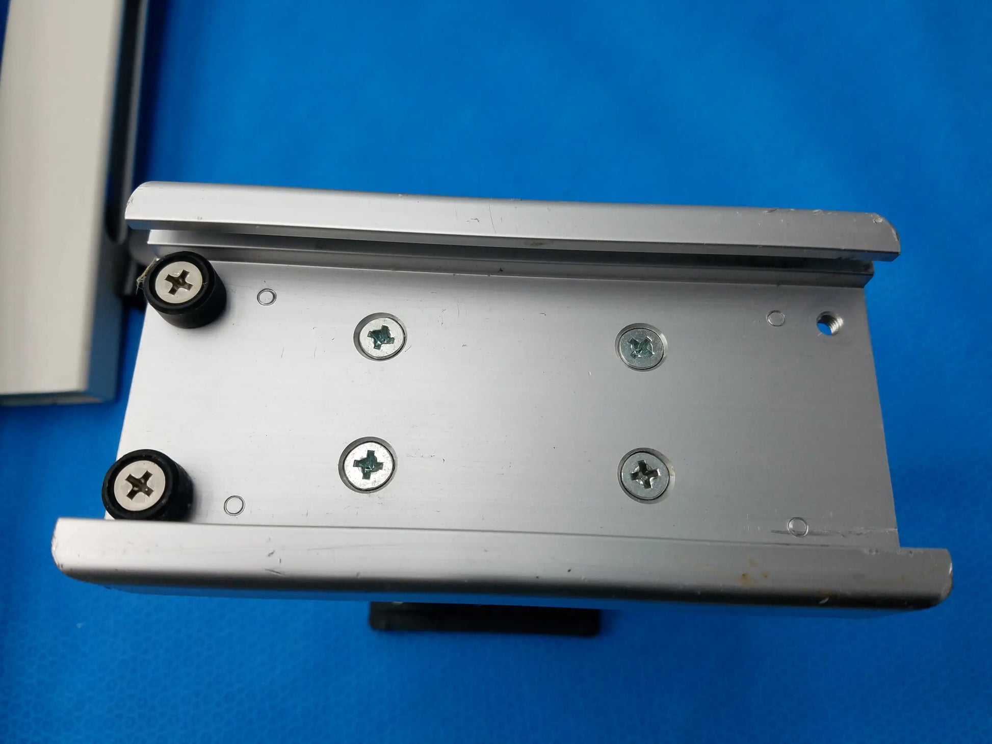 Silver aluminum mounting bracket with black rubber caps on screws for burton medical outpatient ii examination light wall mount assembly