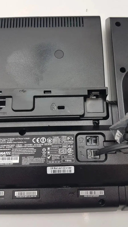 Black lenovo thinkpad laptop with matte finish and visible underside ports shown alongside a color office phone base