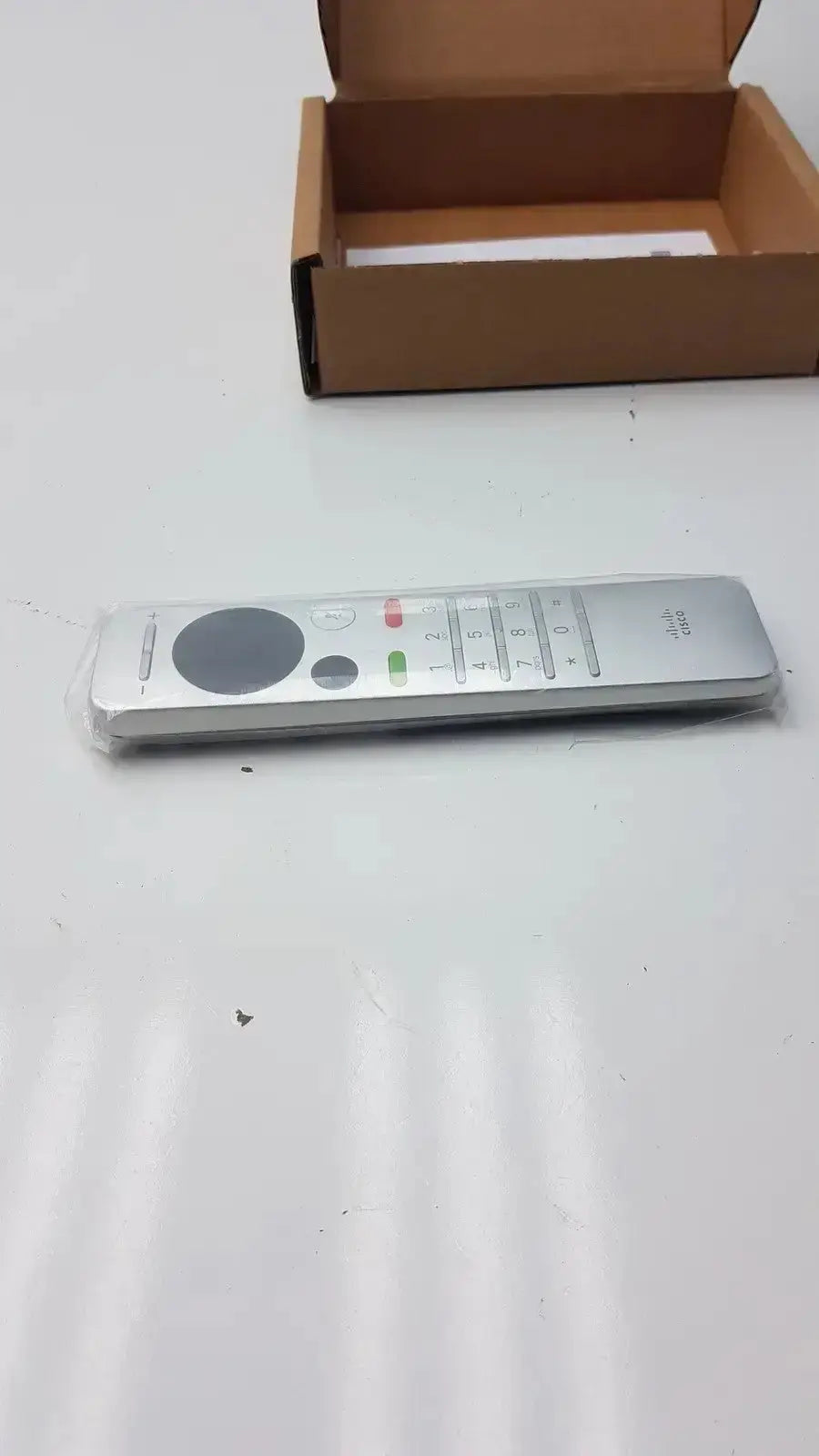 Silver cisco cts-rmt-trc6 remote control with circular navigation pad and colored function buttons for telepresence use