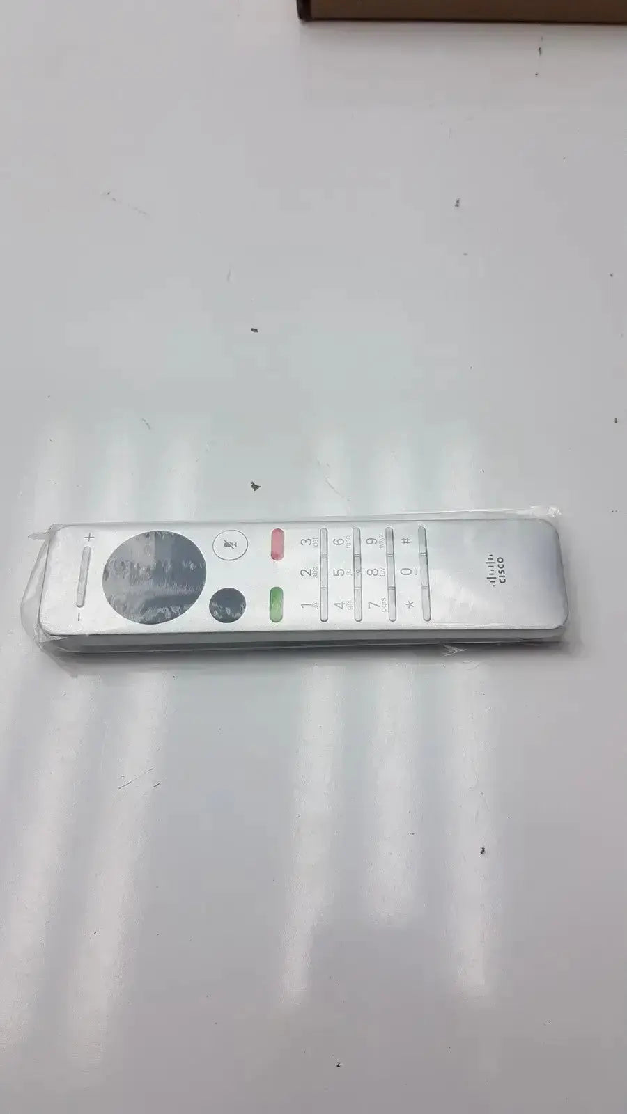 Silver cisco cts-rmt-trc6 remote control with a circular navigation pad and color-coded buttons for telepresence use