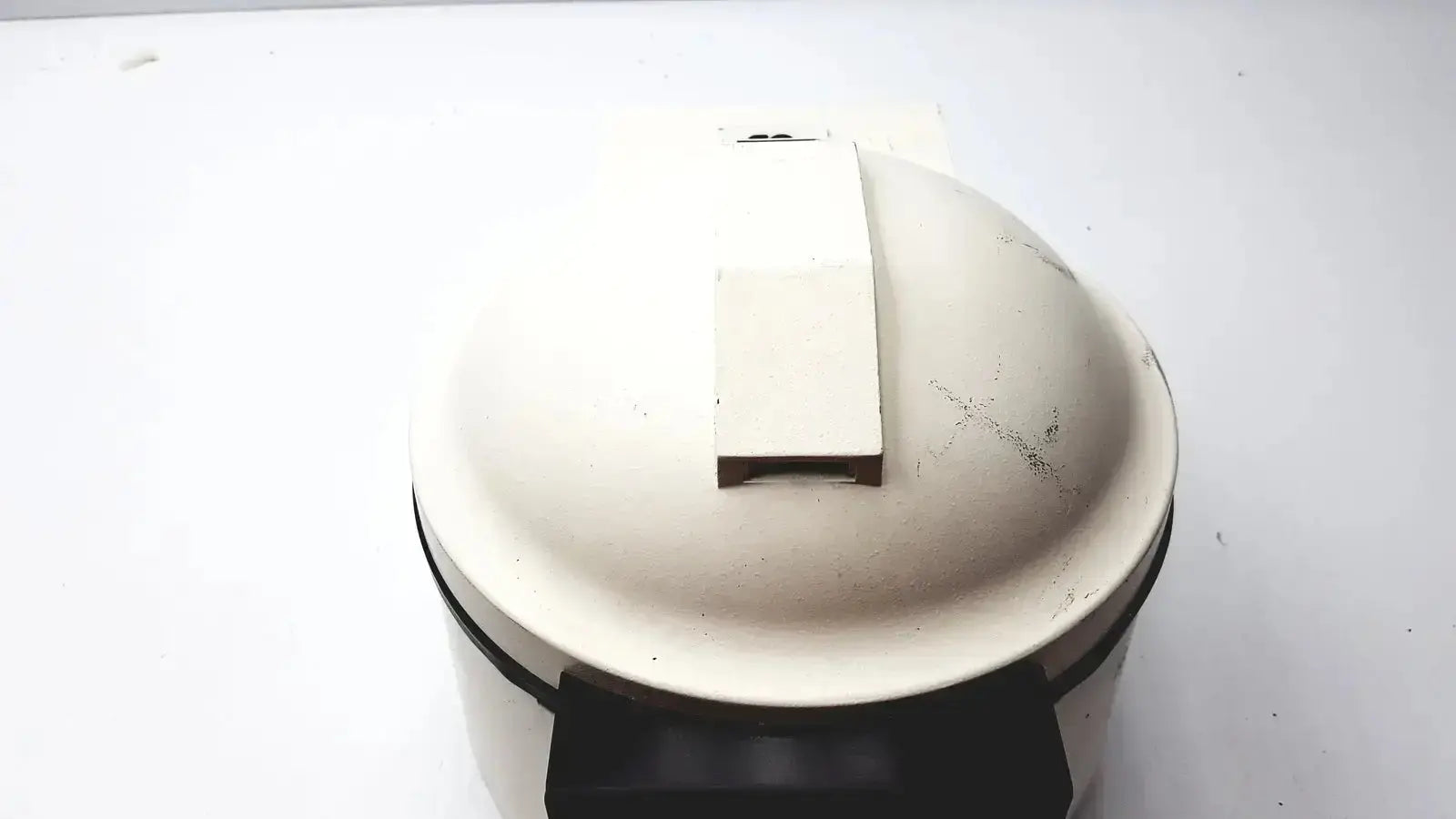 Cream-colored ceramic waffle iron with black handle and lid latch associated with clay adams becton dickinson product