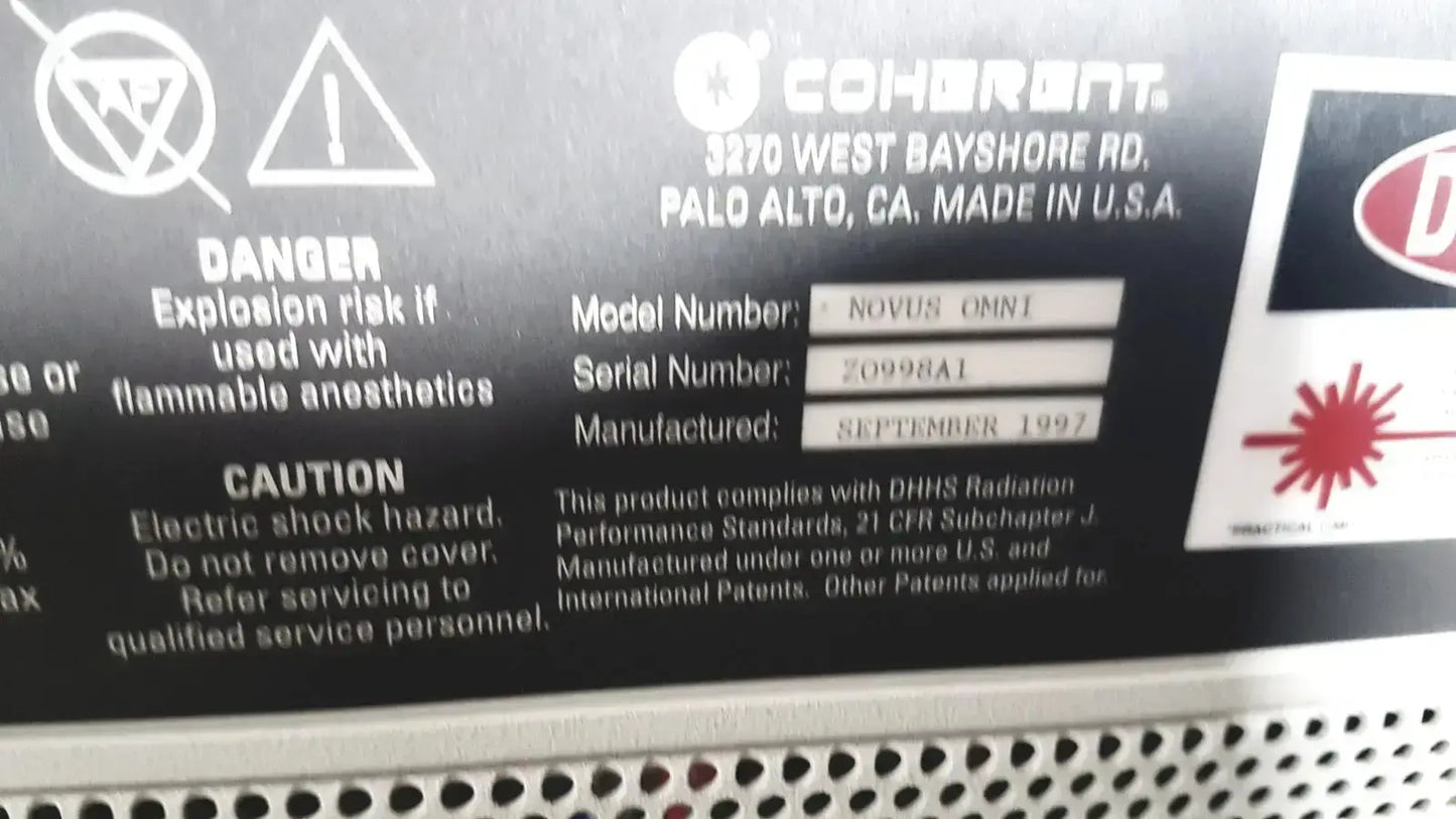 Black coherent novus omni laser device label with white text and warning symbols on novus omni ophthalmic system back side