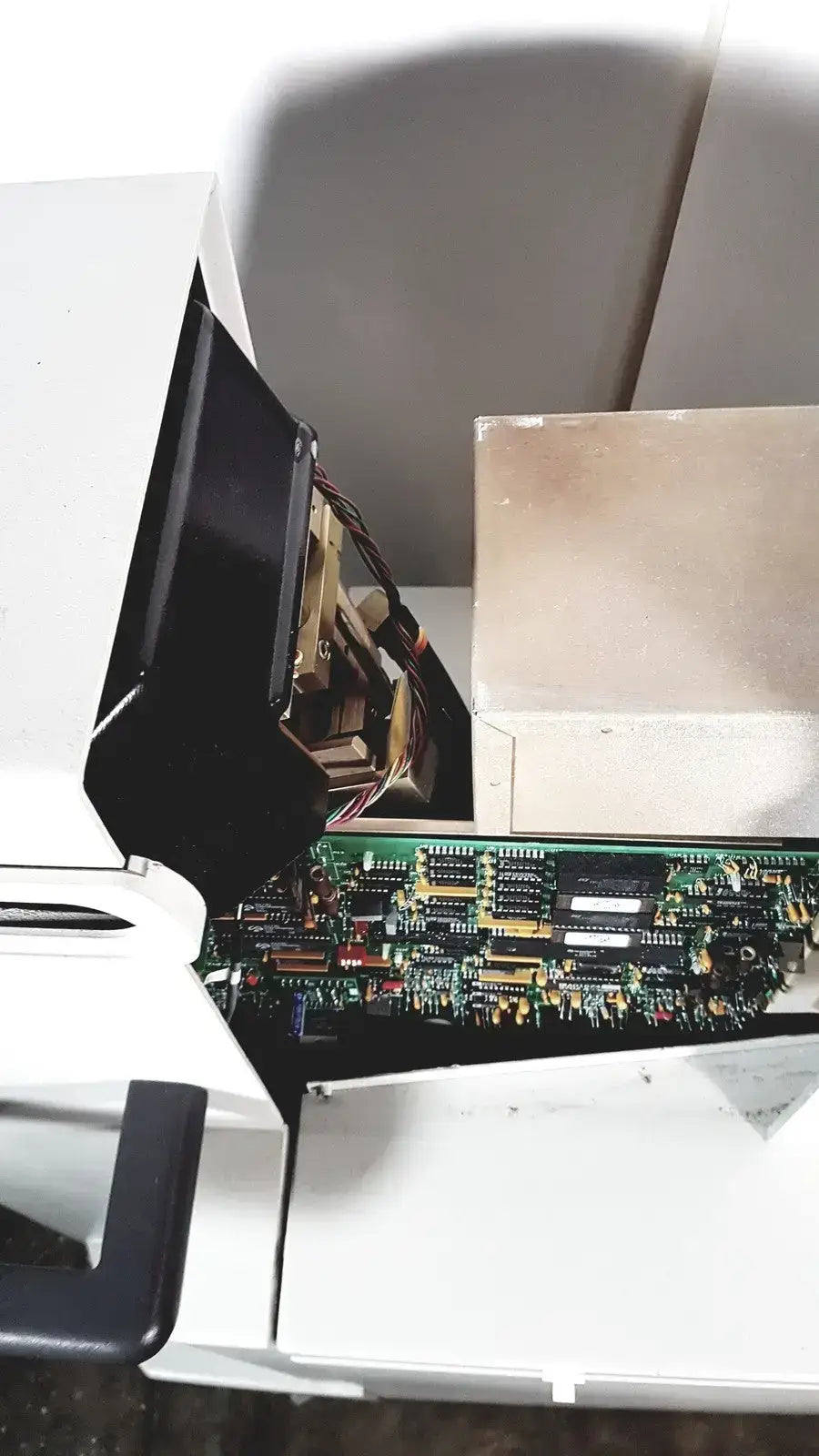 A green circuit board with black and gold components inside a white coherent novus omni opthalmic photocoagulation laser system