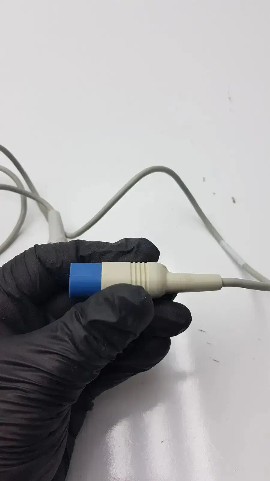 Gray compatible Drager spo2 extension cable with blue and beige connector held in black gloves for SpO2 sensor use