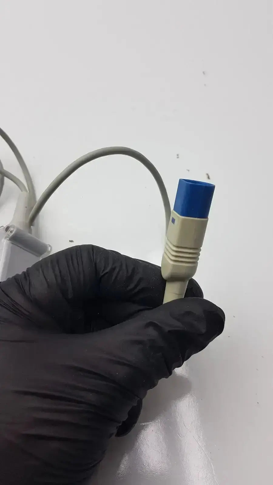 Beige medical spo2 extension cable with blue connector held by black-gloved hand compatible with drager sensor