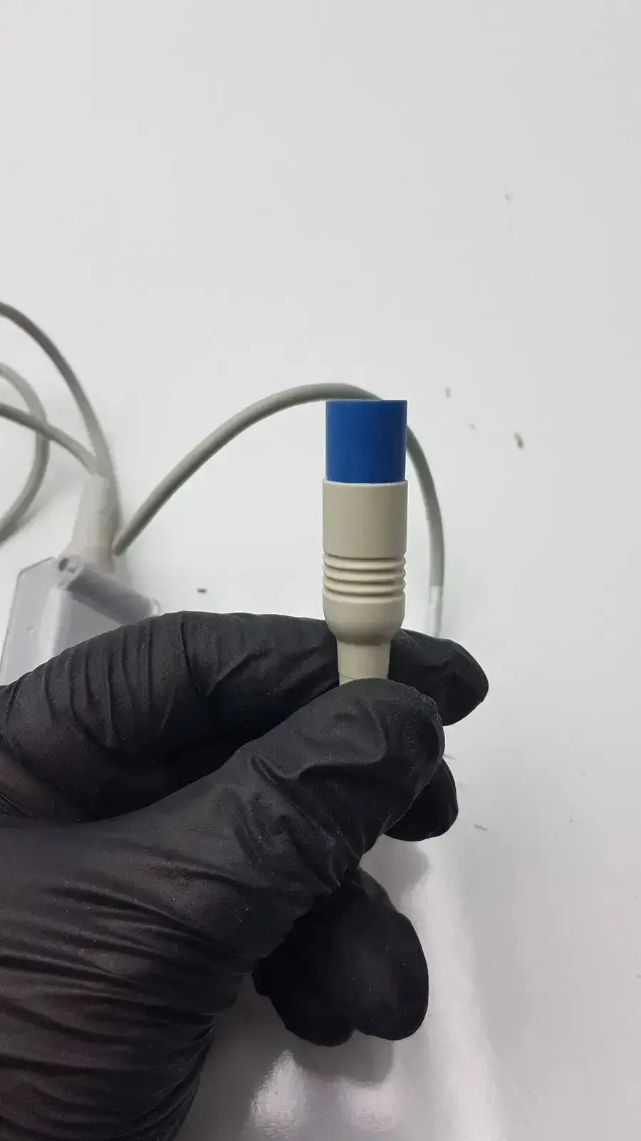 Blue and beige compatible drager spo2 extension cable held in gloved hand for spo2 sensor connection use