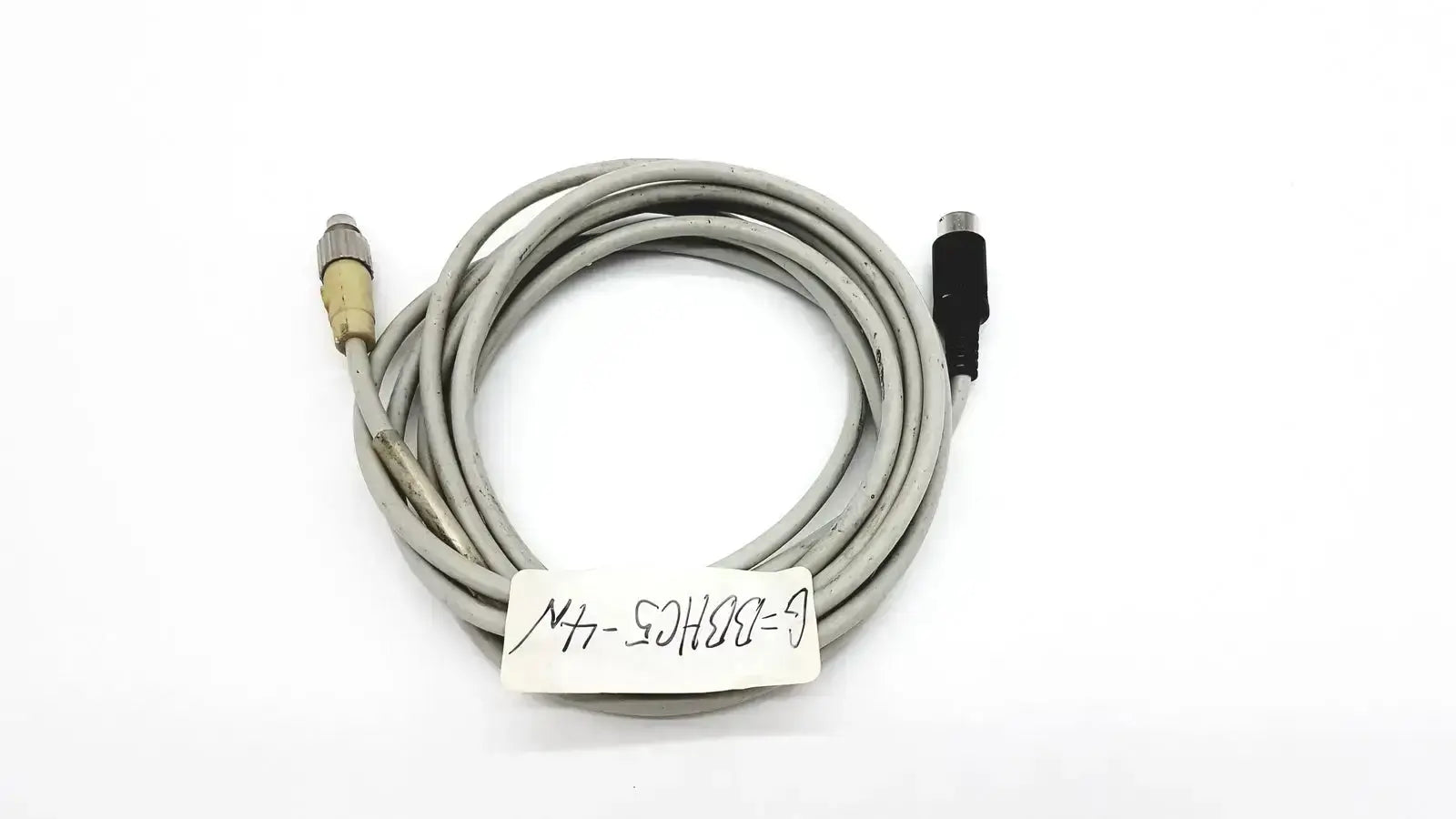 Gray control techniques connecting cable coiled with one metallic and one black connector for industrial use