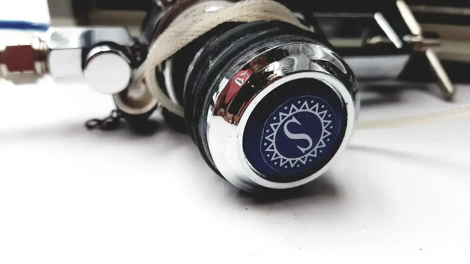 Chrome-finished tattoo machine with blue emblem featuring stylized s and geometric patterns for cosmed quark b2 pulmonary use