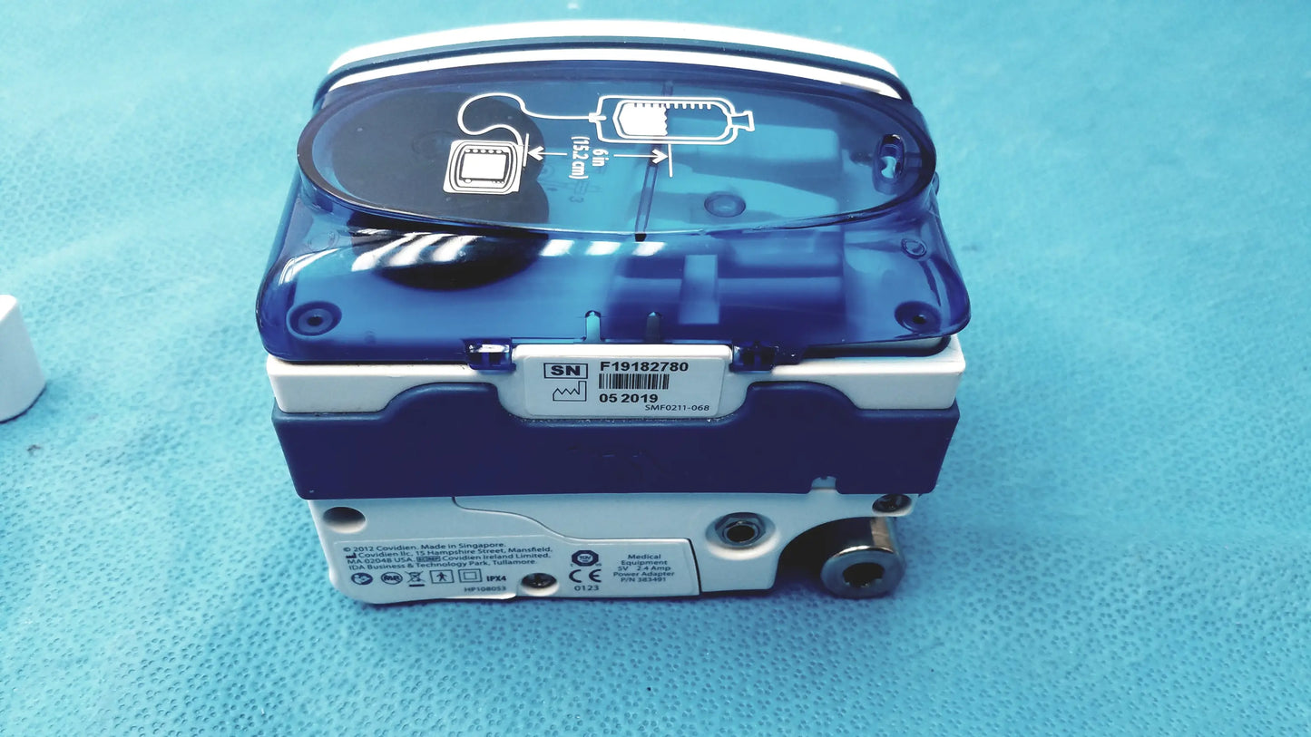 Blue and white covidien kangaroo joey enteral feed and flush pump with transparent lid and pole clamp shown