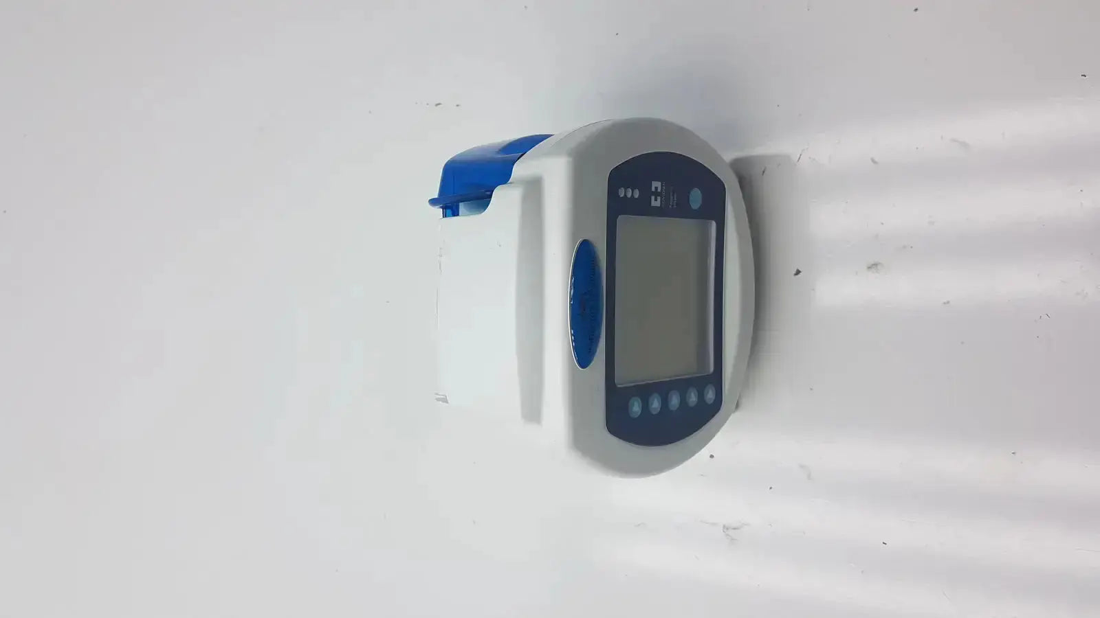 White and blue digital blood pressure monitor with rectangular screen and circular buttons used with Covidien Kangaroo enteral feeding pump