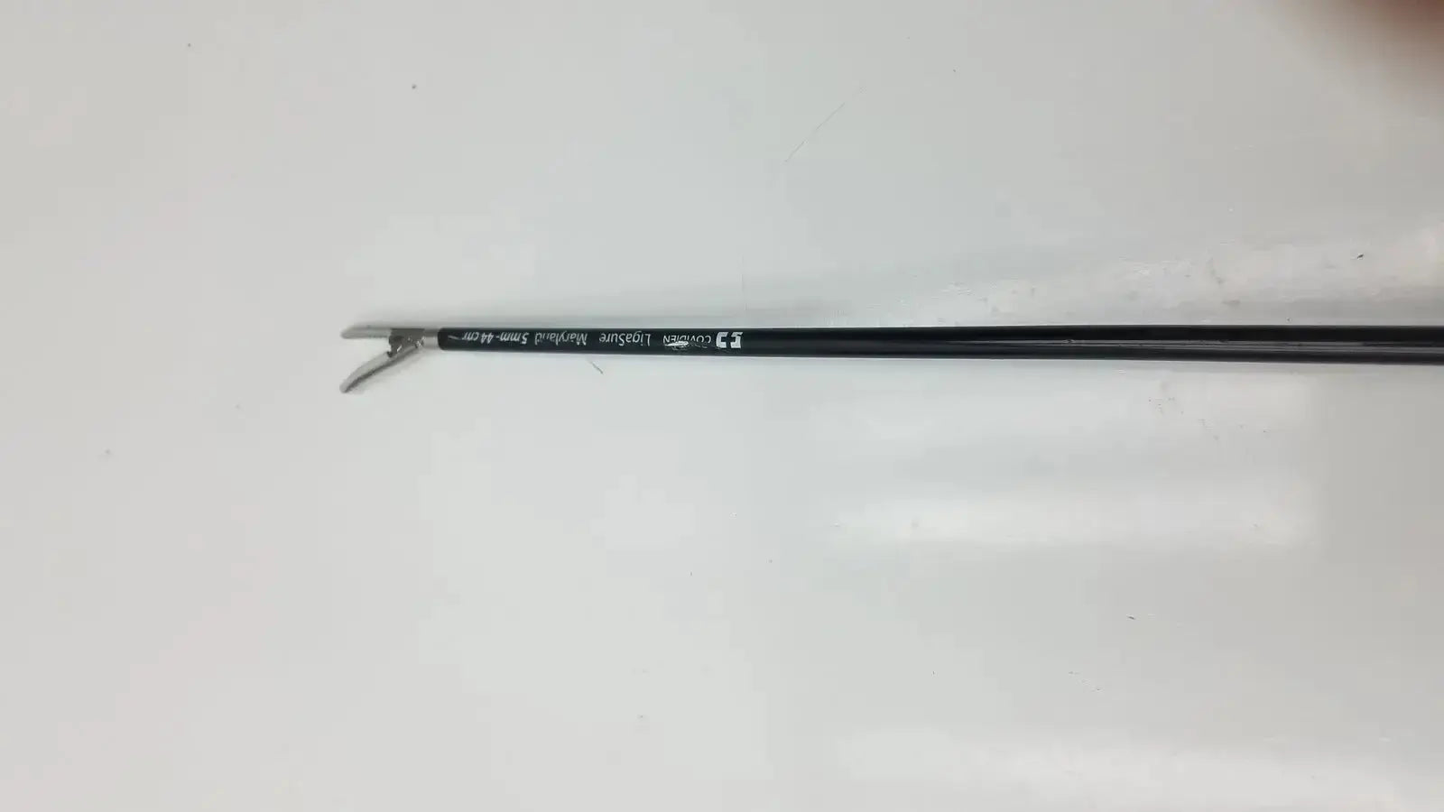 Black-handled covidien ligasure maryland jaw sealer divider with metallic curved tip and engraved text on shaft