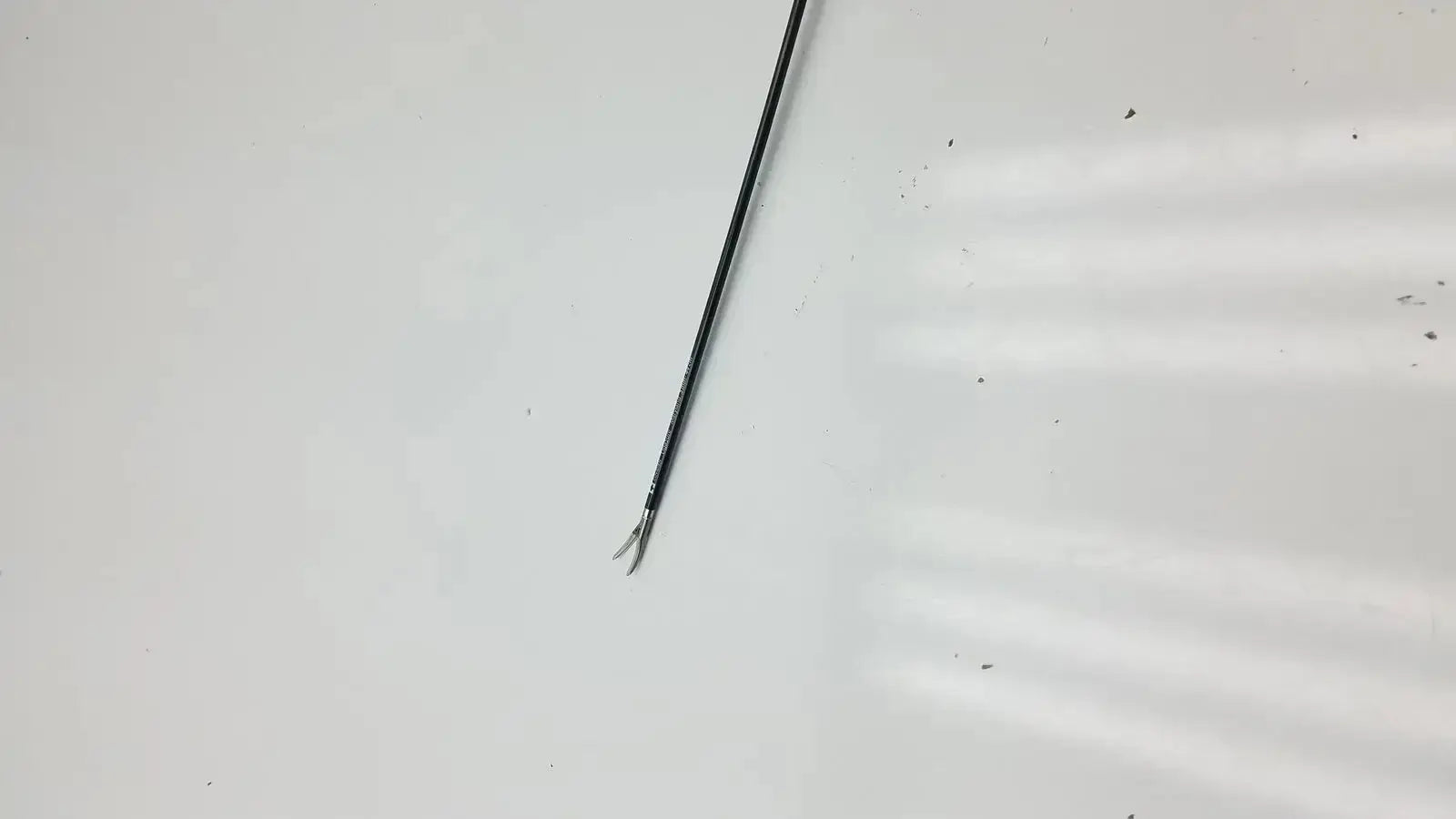 Black metal covidien ligasure maryland jaw sealer divider with slender curved tip and fine serrations along shaft