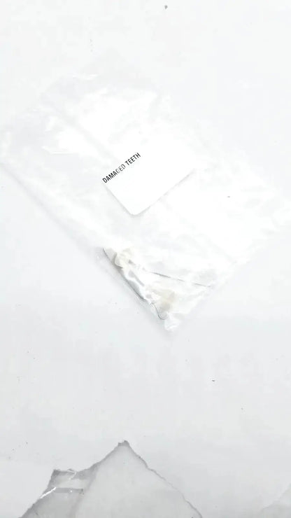 A white translucent plastic bag containing a small metallic dental appliance labeled damaged teeth for damaged teeth portrait ipn