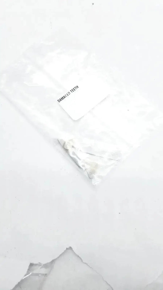 A white translucent plastic bag containing a small metallic dental appliance labeled damaged teeth for damaged teeth portrait ipn