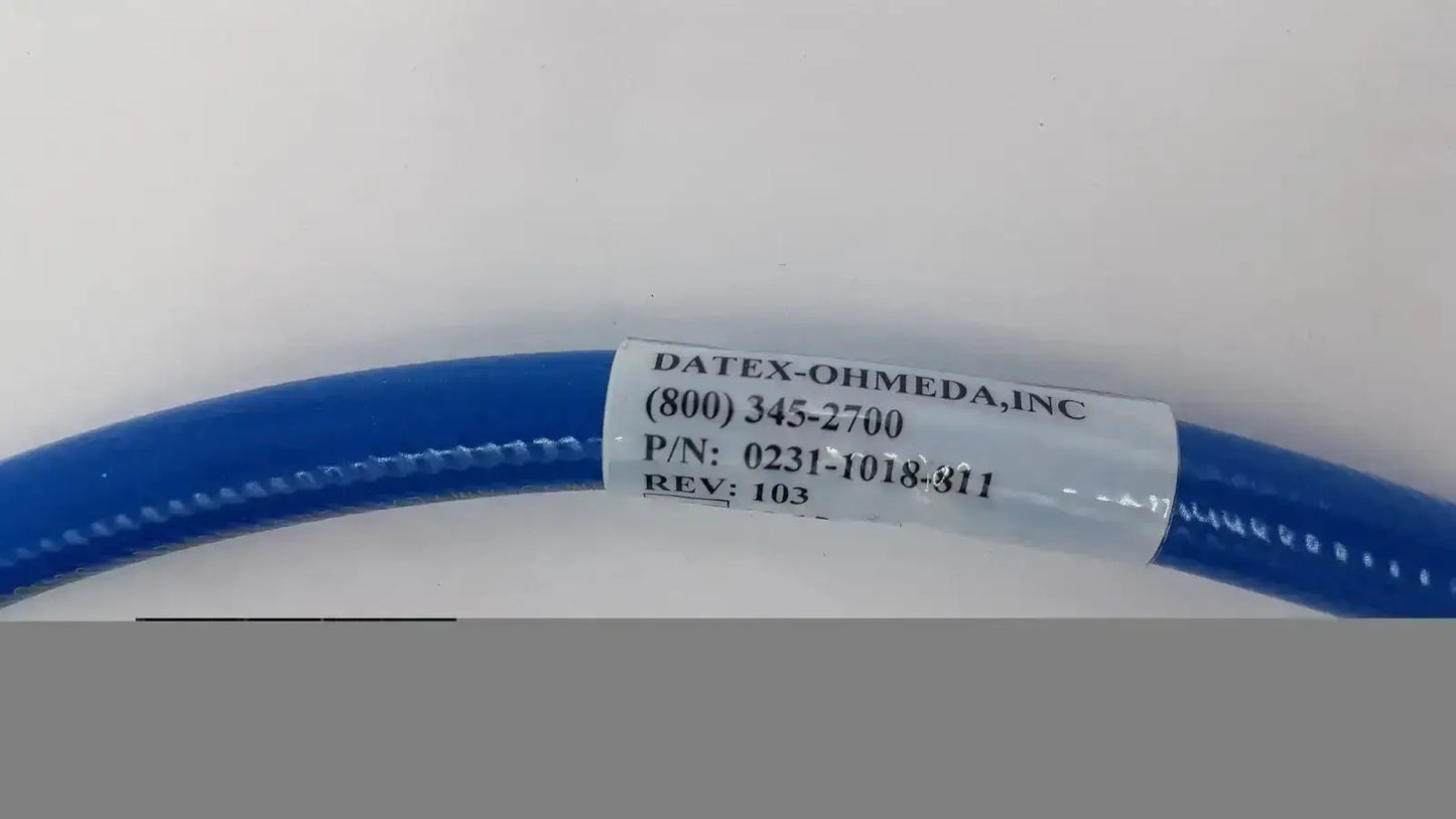 Blue coiled datex ohmeda hose assembly with white label showing manufacturer and part number for hospital surplus use