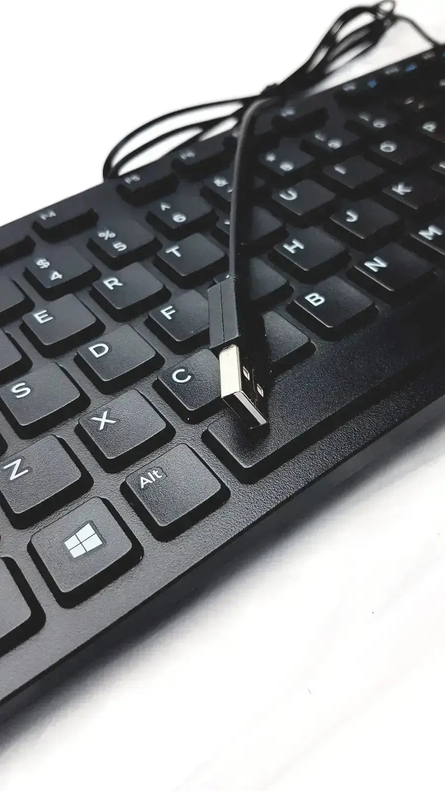 Black usb-a to usb-b cable resting on a matte black dell kb216-bk-us wired keyboard with white lettering keys
