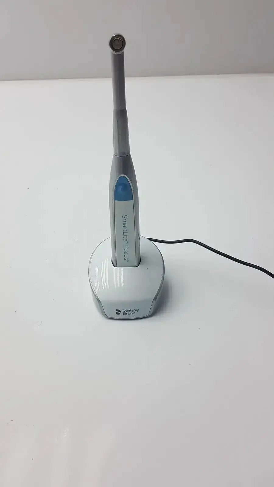 Dentsply sirona smartlite focus dental curing light in silver and blue with ergonomic design on matching charging base