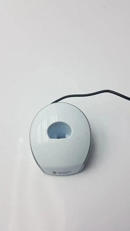 White ceramic toothbrush holder with rounded design and central slot for brushes, complementing dental curing light use