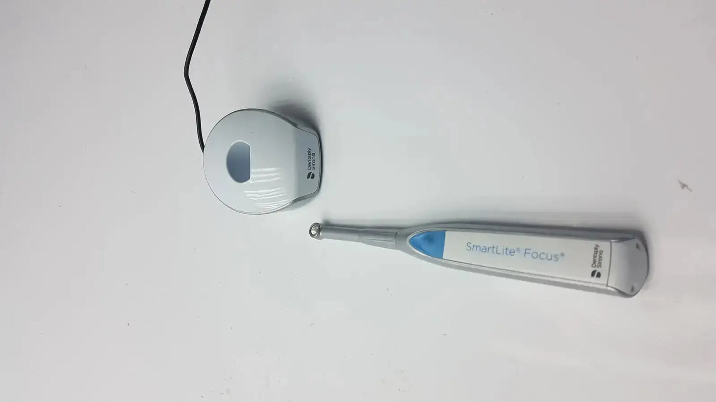 Silver and blue dentsply sirona smartlite focus dental curing light handpiece with matching charging base for dental curing