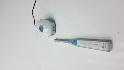 Silver and blue dentsply sirona smartlite focus dental curing light handpiece with matching charging base for dental curing