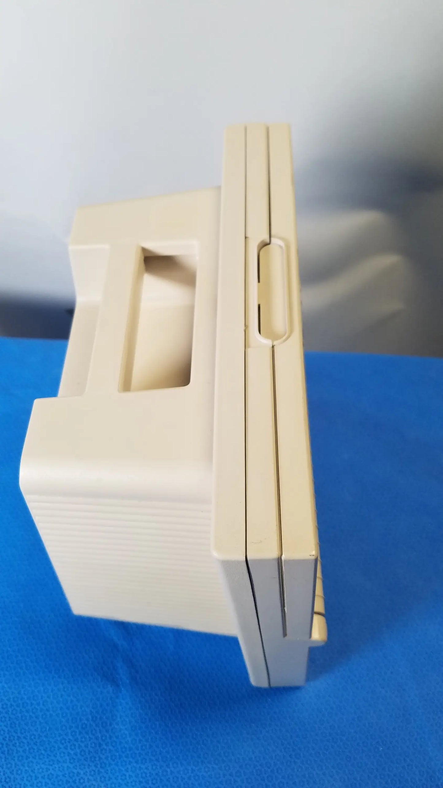 Beige plastic nintendo game boy advance sp console with distinctive hinge and slot design related to reuse medical equipment