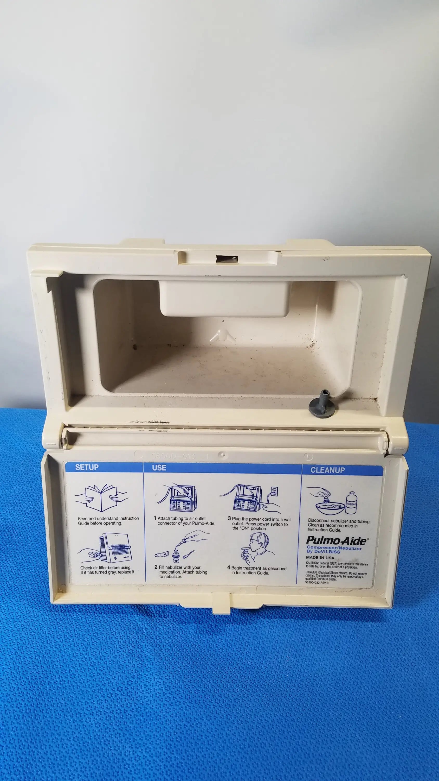 Beige plastic case of DeVilbiss 5650D pulmo-Aide compressor nebulizer system showing instructional diagrams reuse medical equipment