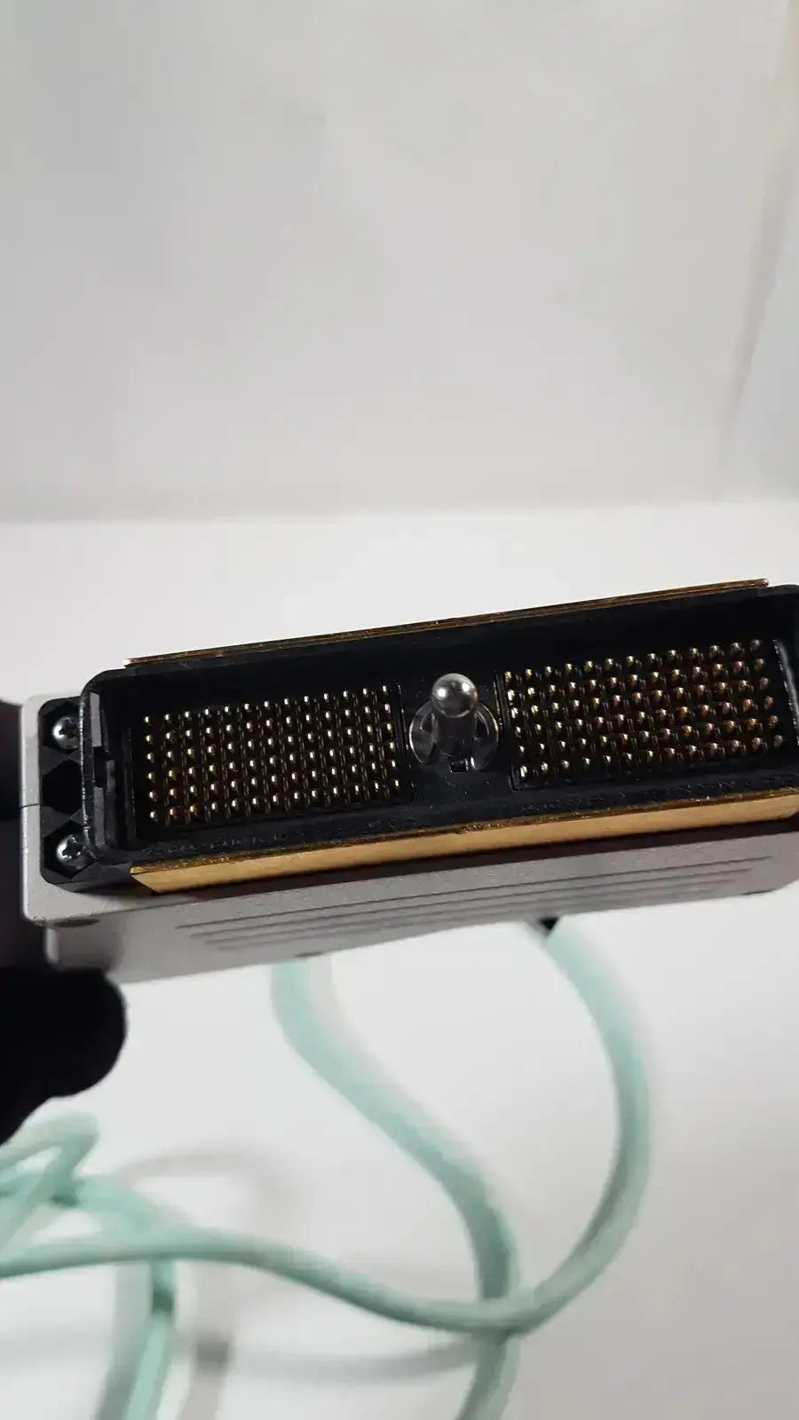 Black rectangular connector with gold pins and central silver sphere on metallic housing of dornier curved array ultrasound transducer