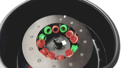 Black cylindrical laboratory centrifuge housing a circular metal plate with red and green caps for used medical equipment sale