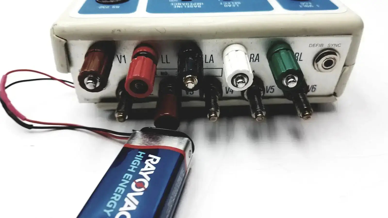 A blue and silver rayovac battery in front of a beige dynatech nevada 215a portable lightweight respiratory patient simulator