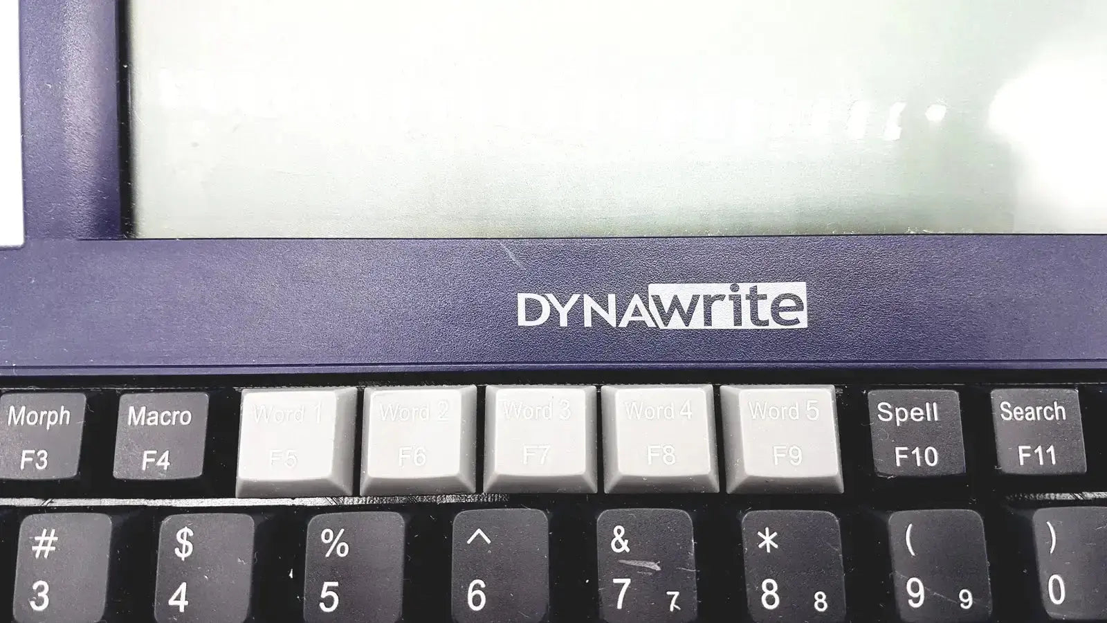 Dark blue dynawrite speech processor laptop keyboard with black and gray keys featuring white lettering by dynavox dynawrite speech