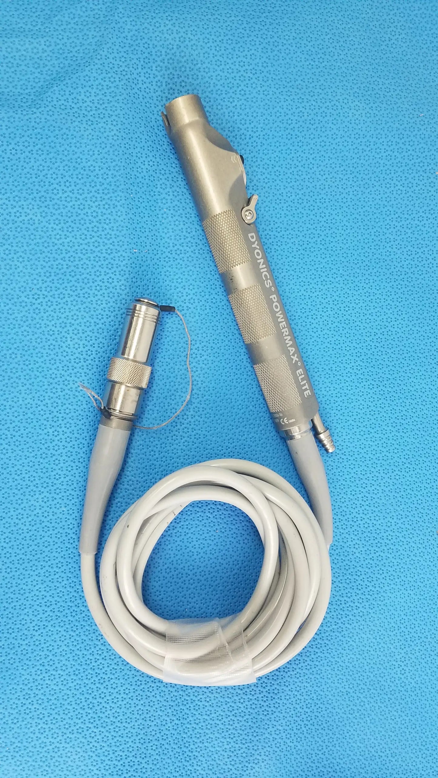Silver metallic dyonics powermax elite shaver handpiece with textured grip and coiled gray cable for medical equipment use