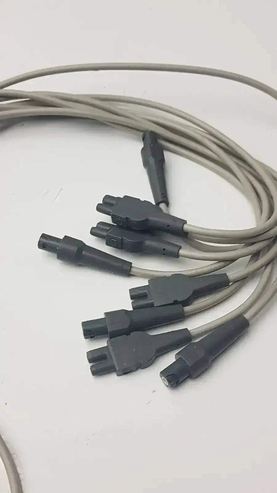 Gray coiled cables with black multi-pronged connectors in an ecg leadwire set cable for vital signs diagnostics