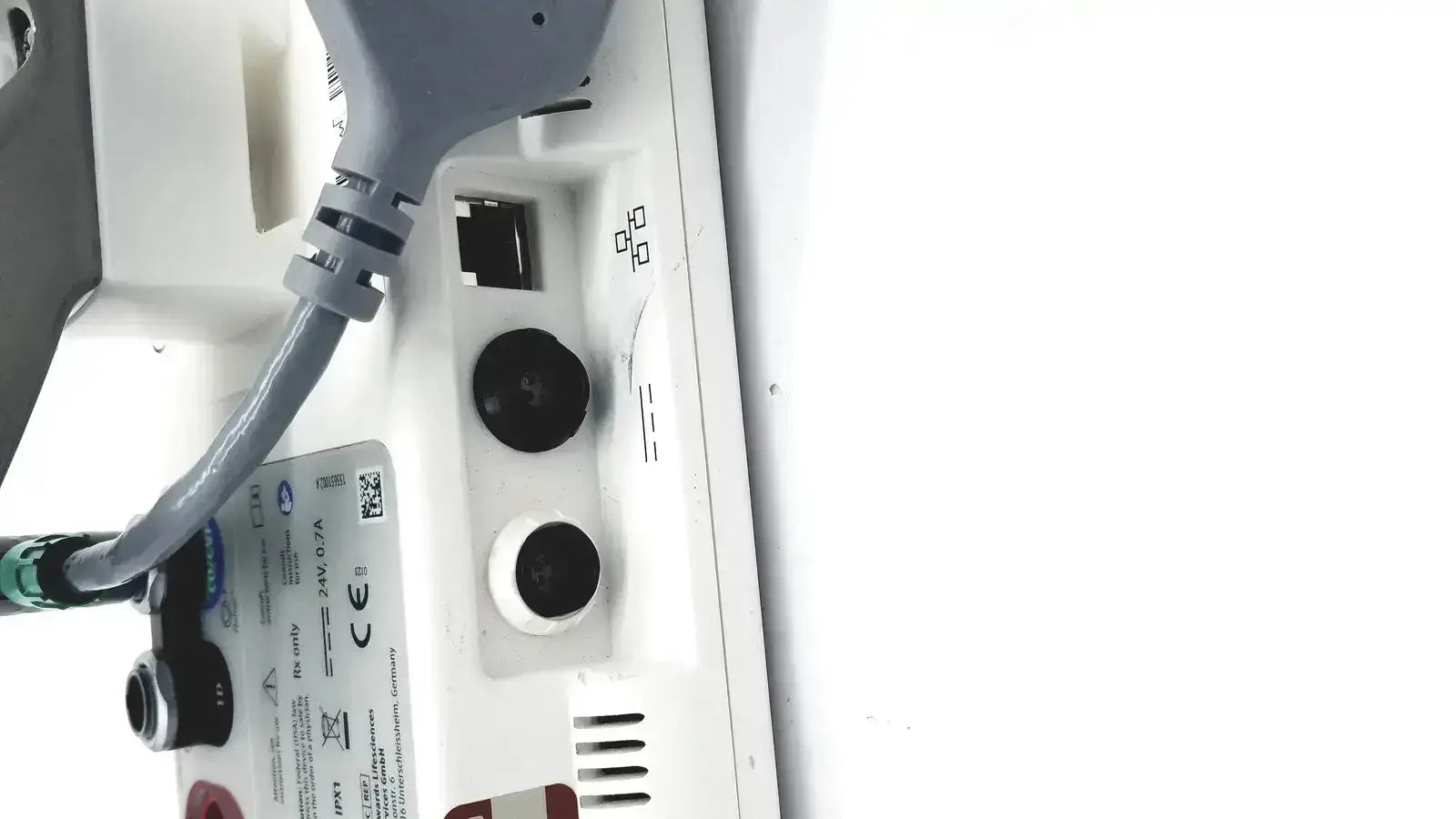 Back side of whitish edwards lifesciences ev1000 databox with gray power cord and plug connected for medical use