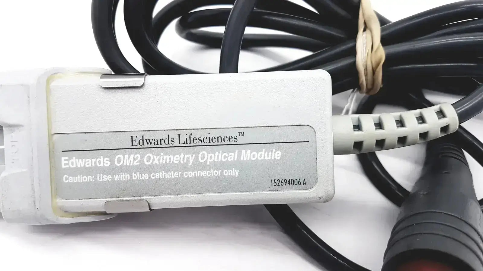 White plastic Edwards Lifesciences OM2 oximetry optical module cable adapter with black coiled cables and beige tie